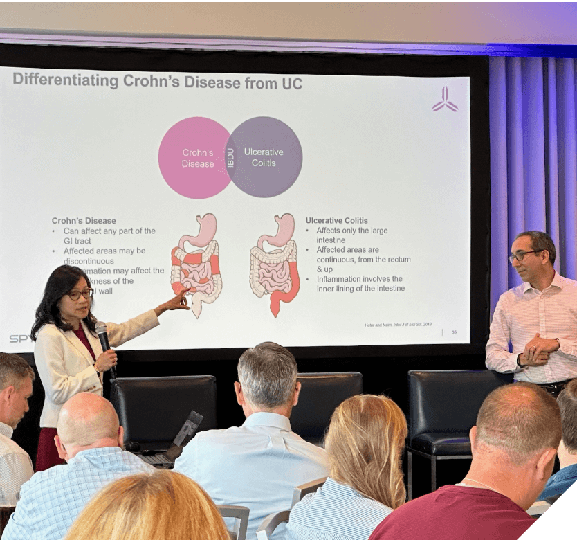 A group of people in front of a large screen discussing the differences between Crohn’s Disease and Ulcerative Colitis.